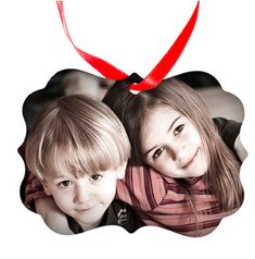 an ornament shaped like a heart with two children on it and a red ribbon around the neck