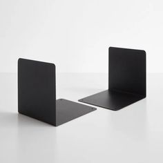 two black bookshelves sitting on top of a white table next to each other