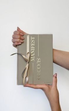 a person holding a book with a ribbon on it's wrap around the cover