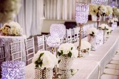 the table is set up with white flowers and crystal candelabras for an elegant wedding reception