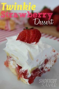 a close up of a piece of cake on a plate with strawberries in the background