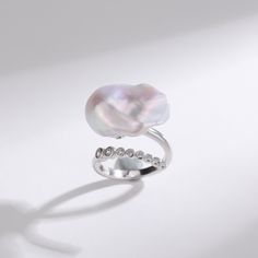 Cessie Ring: Dive into elegance with our Cessie ring, showcasing a striking large baroque freshwater pearl nestled at its heart. Its unique allure is amplified by a gracefully curved arrangement of glistening cubic zirconia, adding just the right touch of sparkle. This masterpiece offers both delicacy and a statement, embodying the perfect balance for modern sophistication Material: 925 Sterling Silver, extra large bold pearl, and cubic zirconia Flexible size with open closure Note: Our jewelry Elegant Baroque Pearl Drop Ring, Elegant Baroque Pearl Open Ring, Baroque Pearl Ring For Anniversary, Elegant Silver Baroque Pearl Rings, Elegant Silver Rings With Baroque Pearl, Elegant Baroque Pearl Ring As A Gift, Elegant Baroque Pearl Ring For Gift, Elegant Baroque Pearl Ring For Wedding, Elegant Baroque Pearl Wedding Ring