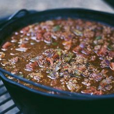 a black pot filled with chili on top of a grill