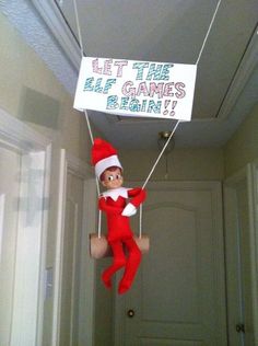 an elf hanging from the ceiling with a sign that says let the elf games begin