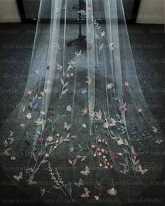 a veil with flowers and butterflies on the floor in front of a window at night