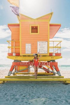 a woman standing in front of a lifeguard tower on the beach