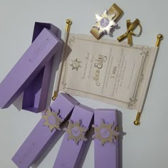 purple paper with gold decorations on it next to an envelope and other items for the ceremony