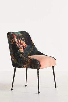 an upholstered chair with flowers on the back and pink seat padding, in front of a white wall