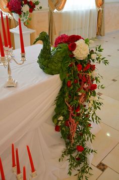 the table is decorated with red and white flowers, greenery and candles for an elegant touch