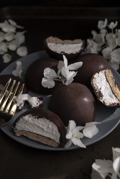 chocolate covered desserts on a plate with white flowers and a fork next to it