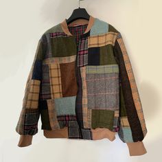 a jacket hanging on a hanger in front of a white wall with a black and brown plaid pattern