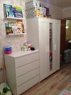 a child's room with white furniture and bookshelves