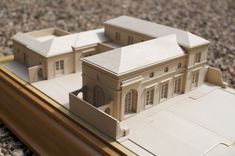 a model of a large building on top of a wooden table next to gravel and rocks