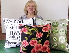 a woman sitting in front of three pillows with flowers on them and the words new york printed on them