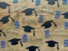 graduation caps and tassels are arranged on a wooden table with the names of graduates