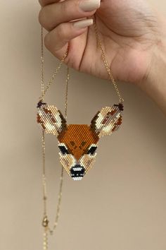 a hand holding a beaded deer head on a chain