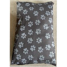 a gray and white dog paw print pillow on the floor with its paws spread out