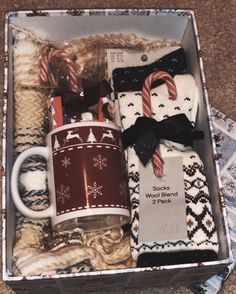 a box filled with sweaters and mugs on top of a carpeted floor