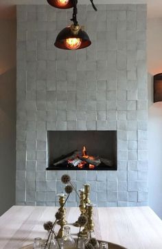 a dining room table with two candles on it and a fire place in the middle