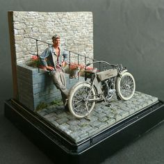 a miniature model of a man leaning on a motorcycle