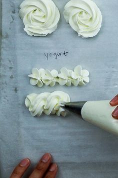 someone is decorating cupcakes with white icing on a sheet of paper