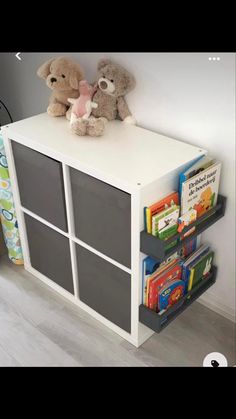 two teddy bears sitting on top of a white book shelf next to a toy bear