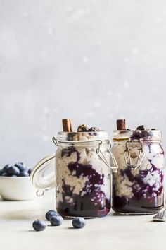 two jars filled with blueberries and oatmeal sitting next to each other