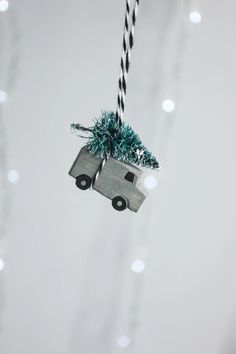 a christmas ornament hanging from a string with a car carrying a tree in it