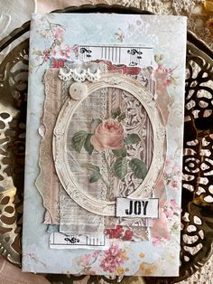 a close up of a card on a table with metal doily and paper flowers