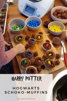 a table topped with lots of cupcakes next to bowls filled with chocolate and candy