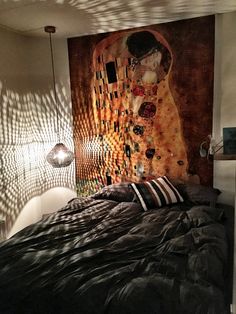 a bedroom with a large painting on the wall above the bed and black comforter