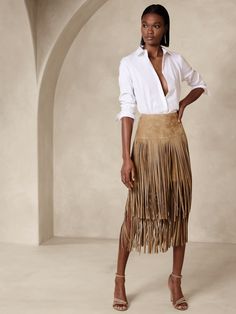 Fantastically feminine in fringe, this romantic creation was destined to sway with long strips of luxurious suede that entice and delight with every movement.  We left the final tier unlined for added drama.  A-LINE: High-waisted.  Flared from waist to hem.  Hidden zip with hook-and-eye closure at wearer's left side.  Lined to the knee.  LEATHER WORKING GROUP: By purchasing this product, you are supporting responsible leather manufacturing through the Leather Working Group.  A-line: High waisted.  Fitted through the waist and hip, gently flared from hip to hem.  Midi length.  Skirt length: Regular 34" Model: Size 2, 5'10" (178cm). Fringe Skirt Outfit, Suede Fringe Skirt, Looks Country, Rodeo Fashion, Western Chic, Fringe Skirt, Velvet Skirt, Suede Skirt, Suede Fringe