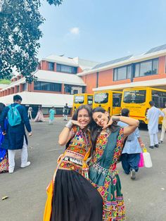 two young women standing next to each other in front of buses and people walking around