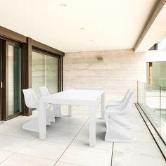 a white table and chairs sitting on top of a tiled floor next to sliding glass doors