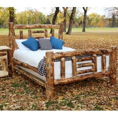 a bed made out of logs with blue pillows on it and two end tables next to it