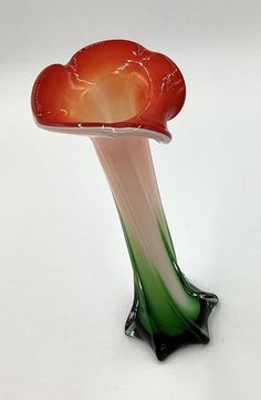 a red and green vase sitting on top of a white table