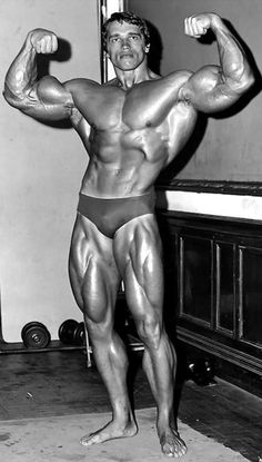 a man with muscles flexing his arms and legs in a gym room, posing for the camera