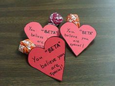 three heart shaped candy candies with words written on them sitting on top of a wooden table