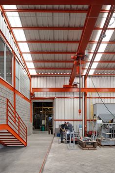 two men are working in an industrial building with orange and white paint on the walls