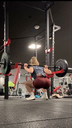 a woman squats down while holding a barbell