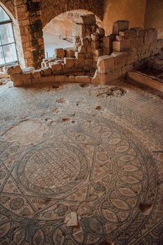 an ancient mosaic in the middle of a room with stone walls and flooring on it