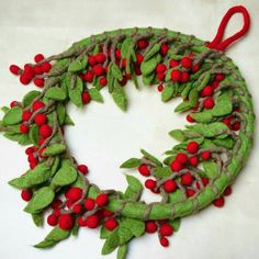 a christmas wreath made out of felt with red berries and green leaves on the front