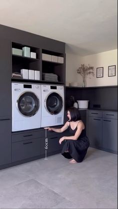 a woman kneeling down in front of a washer and dryer