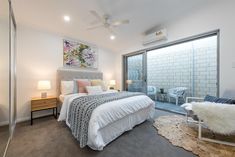 a bedroom with a bed, chair and sliding glass door leading to the outside patio