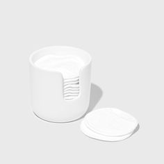 a white cup sitting next to a plate on top of a gray surface with two plates in front of it