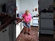 an older woman is standing in the kitchen and talking on her cell phone while wearing a skirt