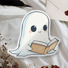 a ghost reading a book while laying on top of a white sheet next to an envelope