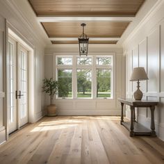 an empty room with wooden floors and white walls, two lamps on either side of the window