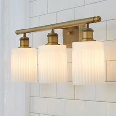 three light bathroom fixture with frosted glass shades on the bottom and brass finish fixtures