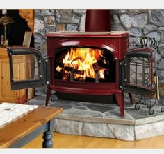 a wood burning stove sitting inside of a living room next to a stone wall and wooden floor